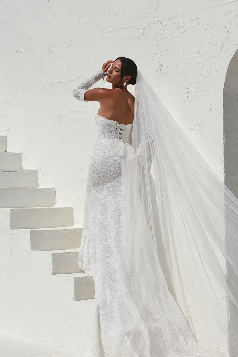 Model is wearing a column wedding dress with 3D florals, sequins, and pearls