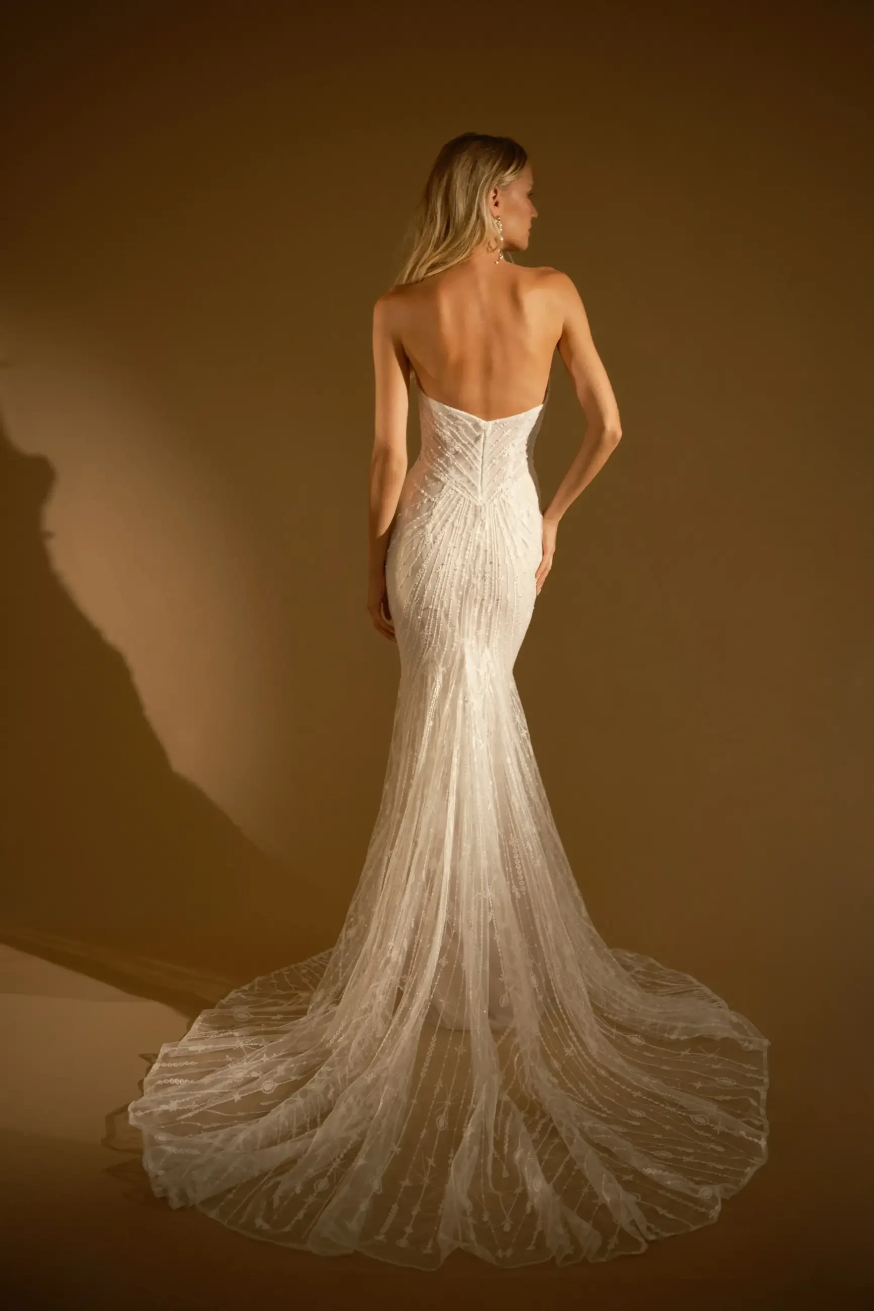 model is wearing a strapless fitted wedding dress by rish bridal