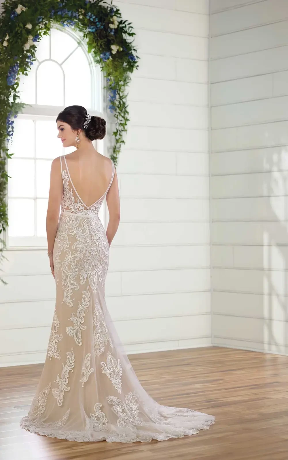 model is wearing a sleeveless open back champagne bridal gown