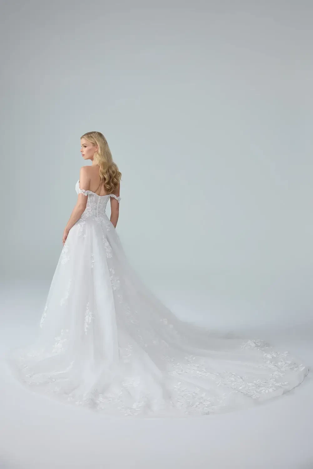 model is wearing a romantic off the shoulder tulle wedding dress