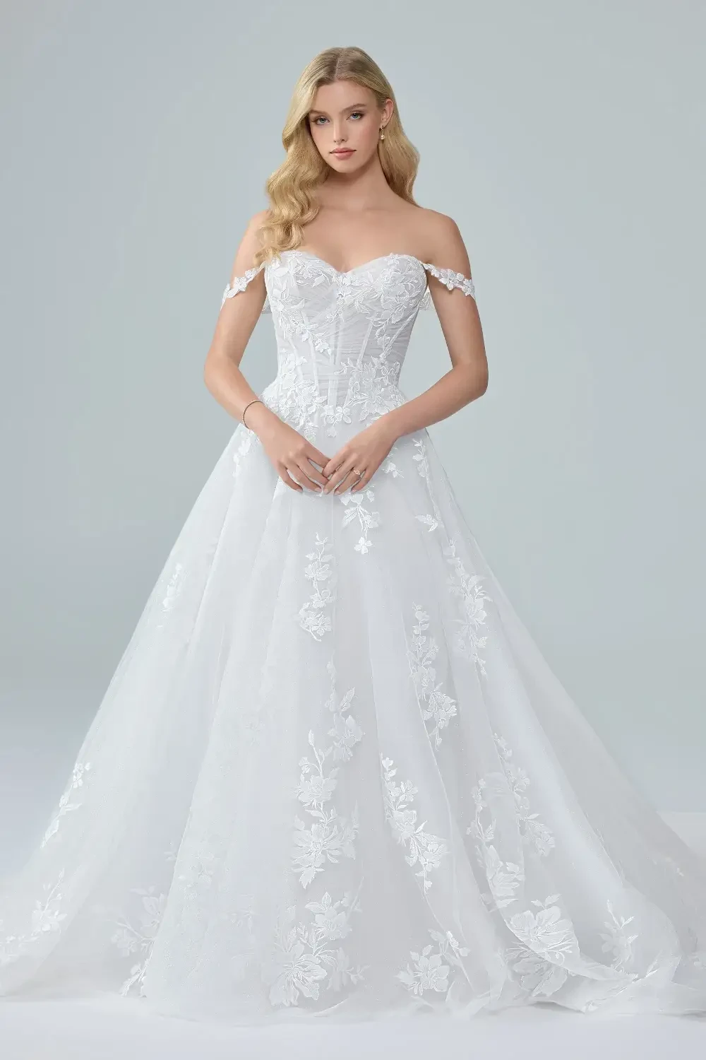 model is wearing a romantic off the shoulder tulle wedding dress