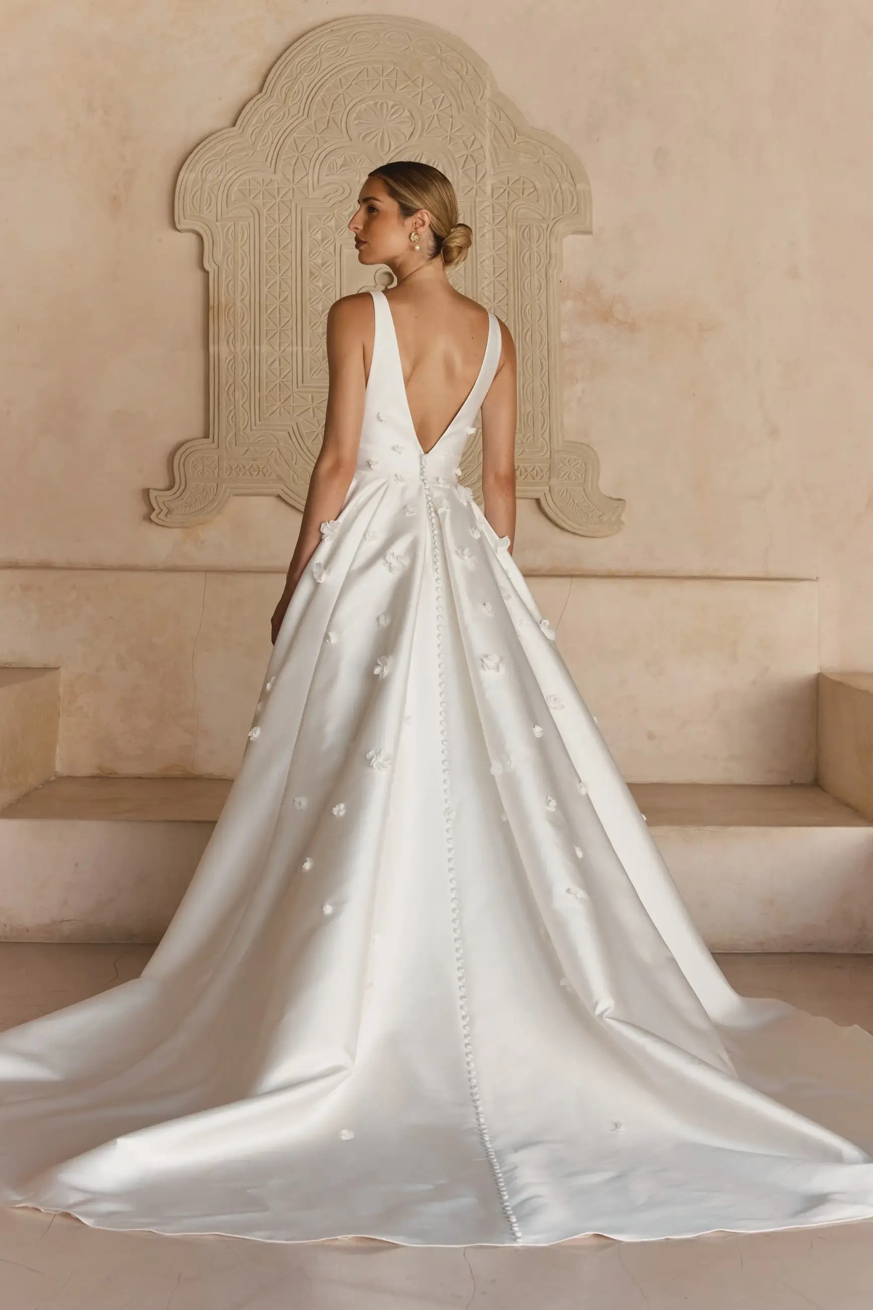 Model is wearing a minimalist mikado wedding dress with an a-line silhouette and 3D florals