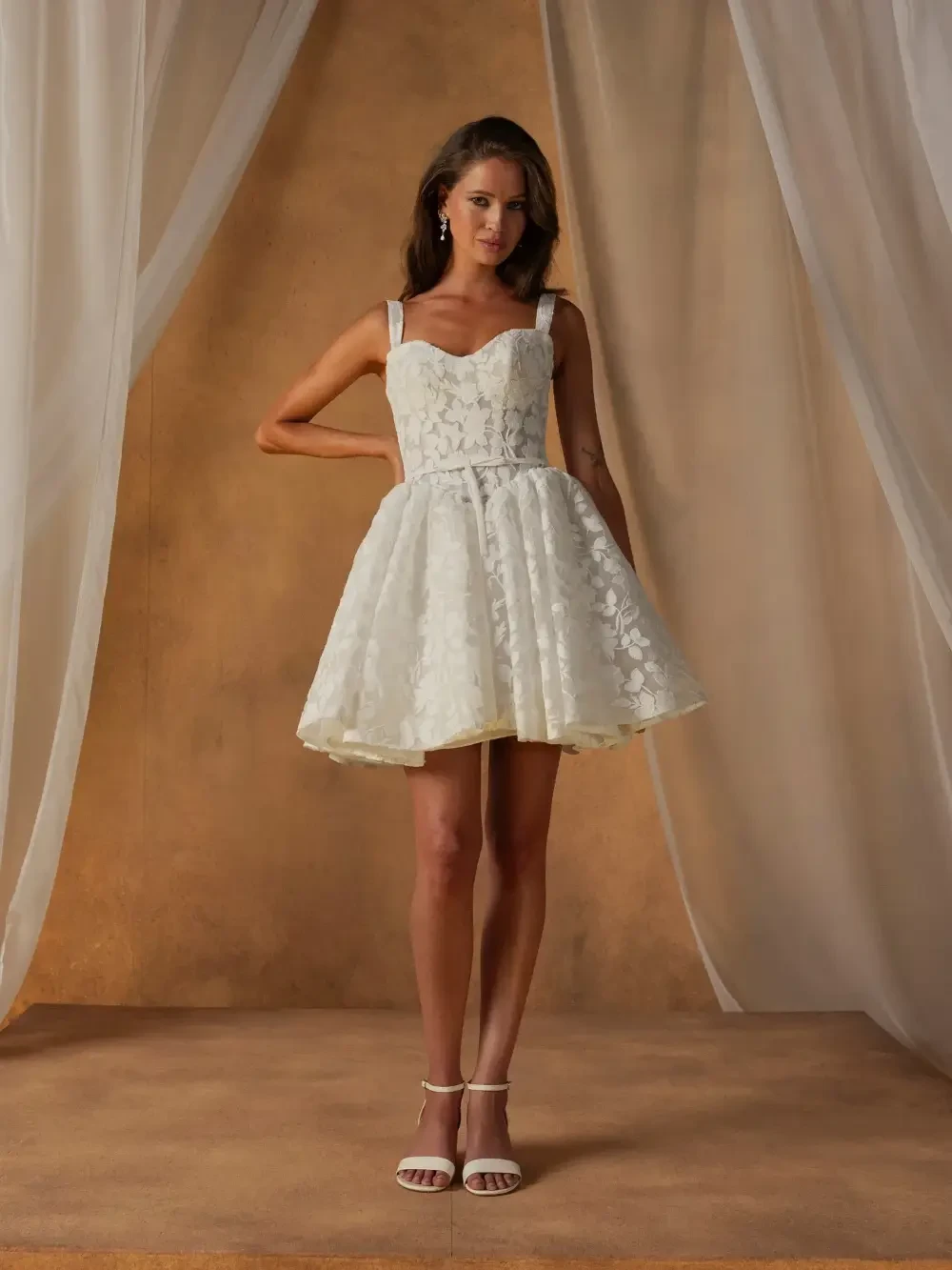model is wearing a sleeveless mini bridal gown